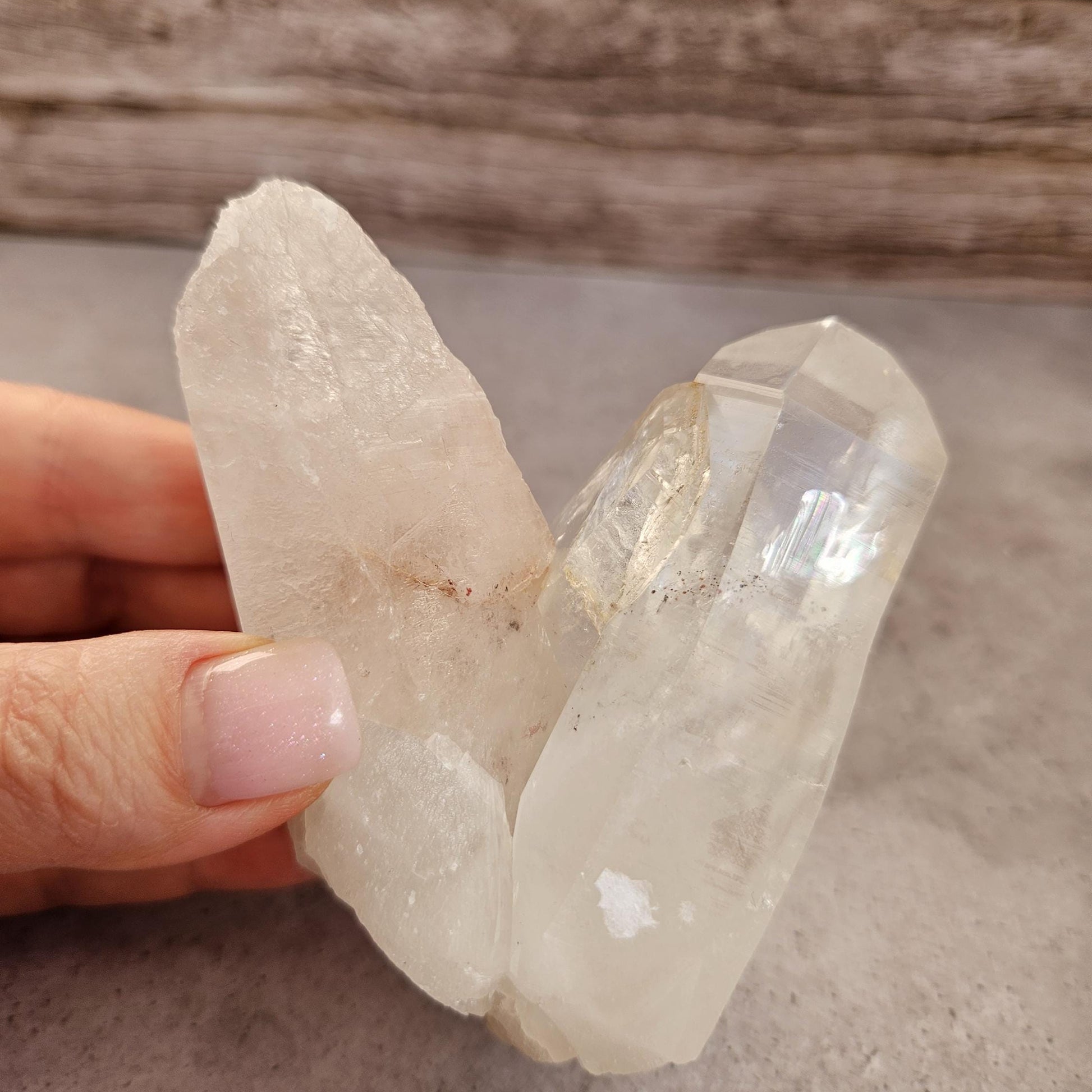Clear crystal rock held by a hand on a neutral background