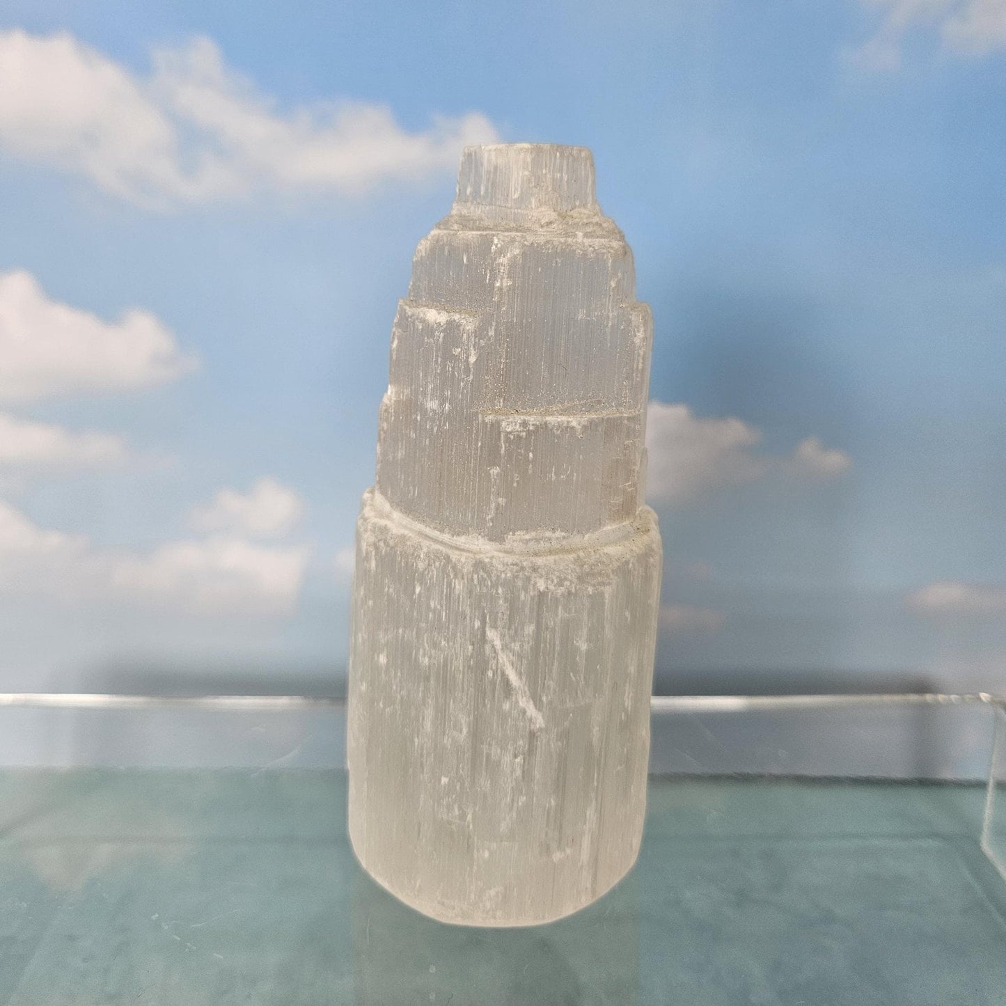 Clear crystal tower on a reflective surface with a blue sky background