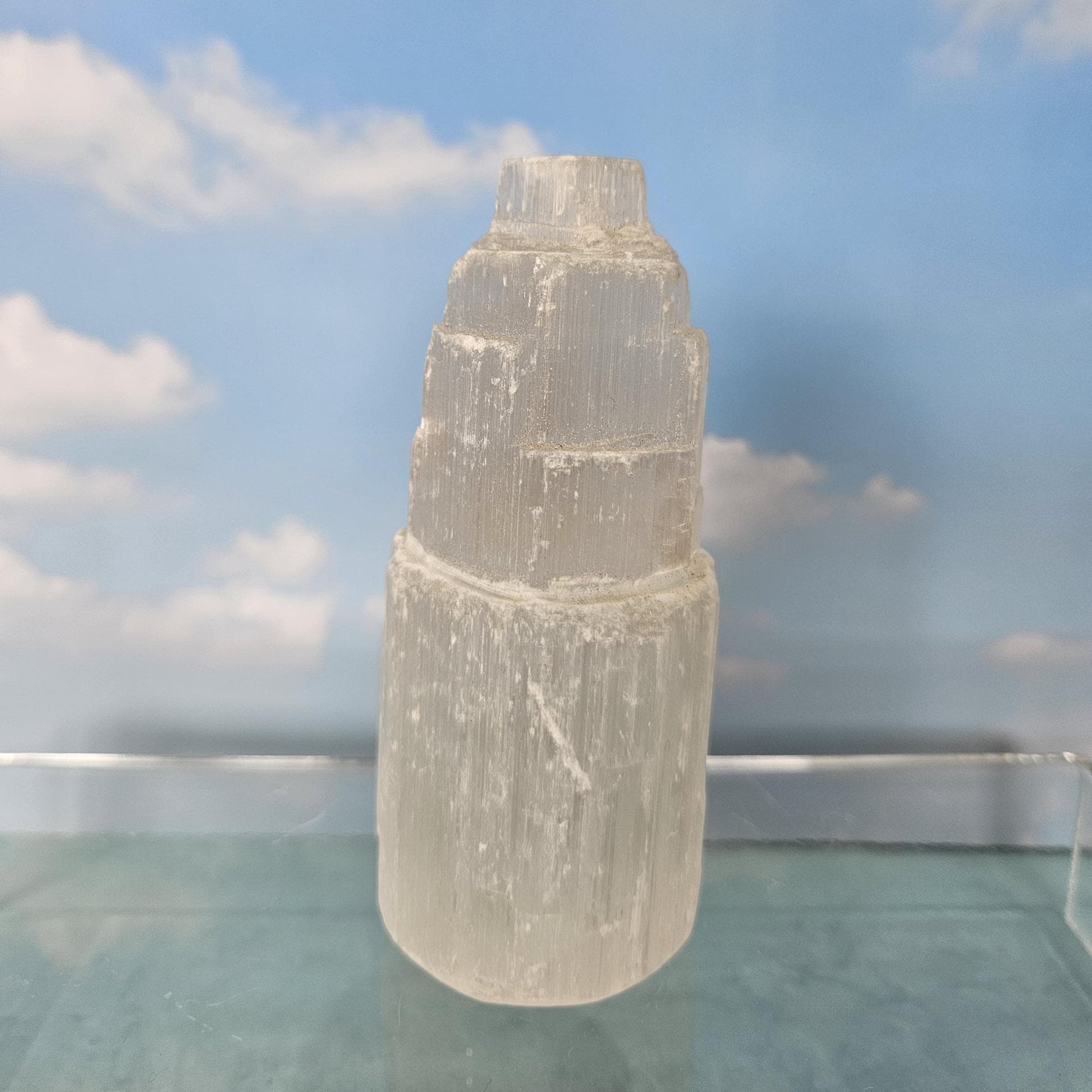 Clear crystal tower on a reflective surface with a blue sky background
