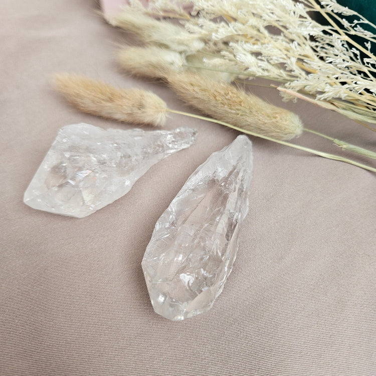 Lemurian crystal points natural raw quartz displayed on a neutral fabric background with dried flowers, natural healing stones for energy and clarity