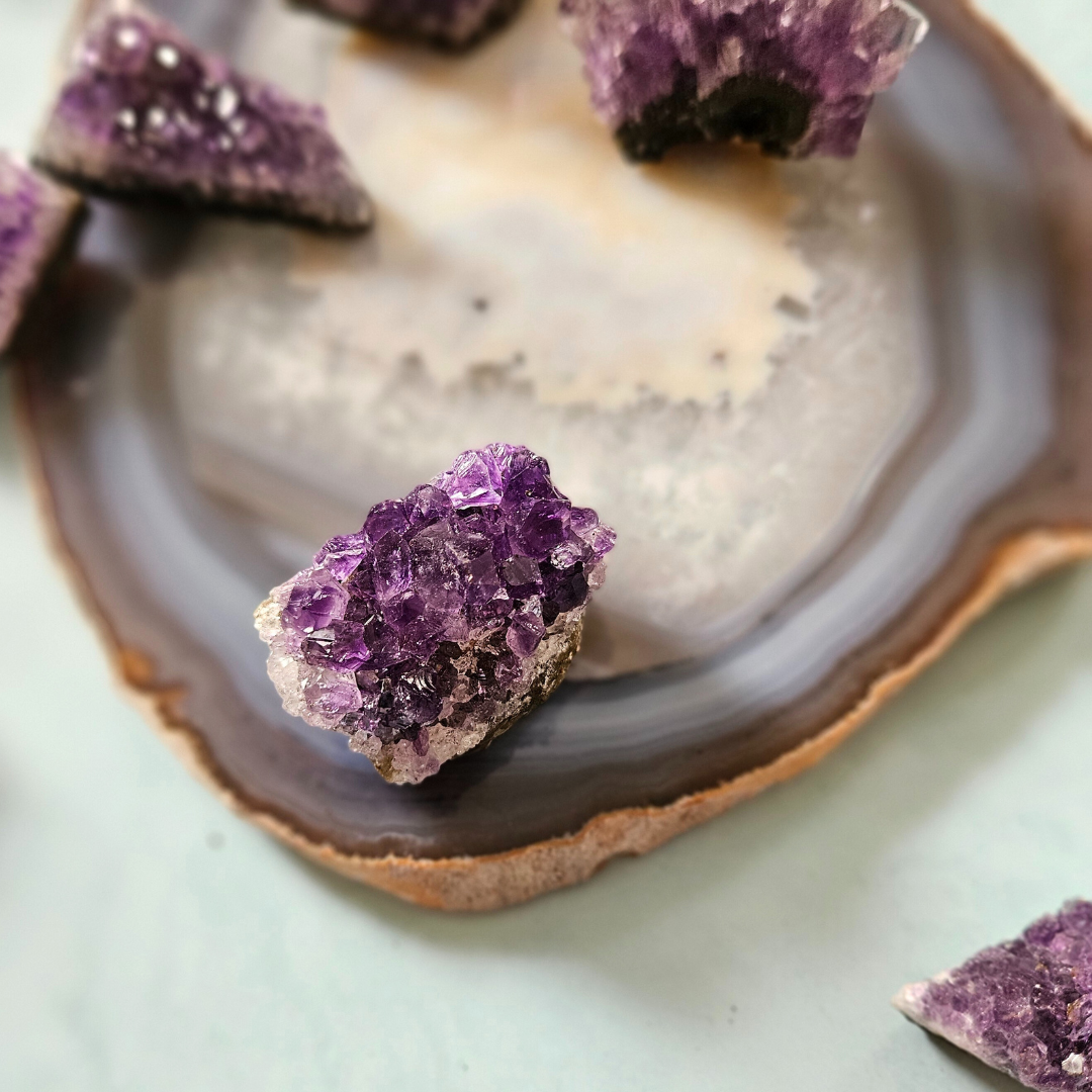 Raw amethyst clusters displayed on agate slice
