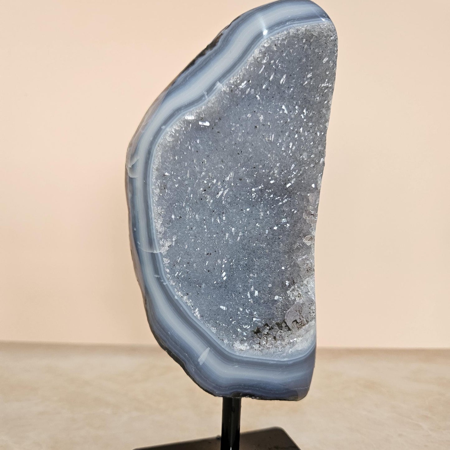 Geode crystal on a stand against a beige background